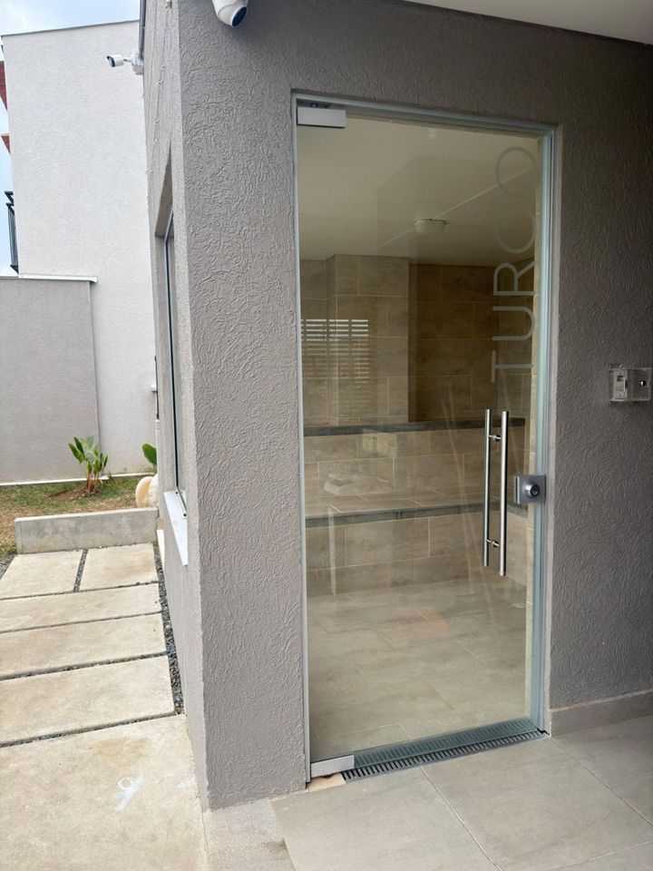 Entrada del baño turco, con puerta de vidrio y bancas en cerámica